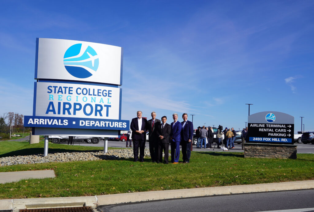 group of people outside of the state college airport sign